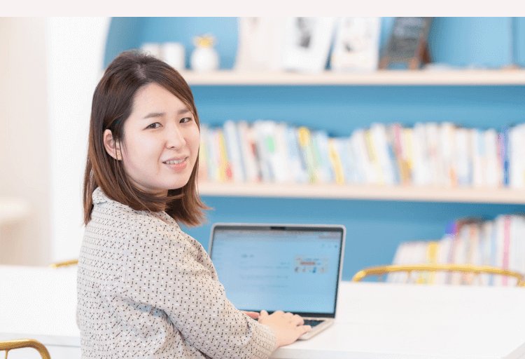 SHElikes拠点の本棚を背にノートPCに向かうあっきーさん