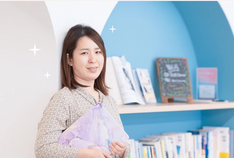 SHElikes拠点の本棚を背に微笑むあっきーさん
