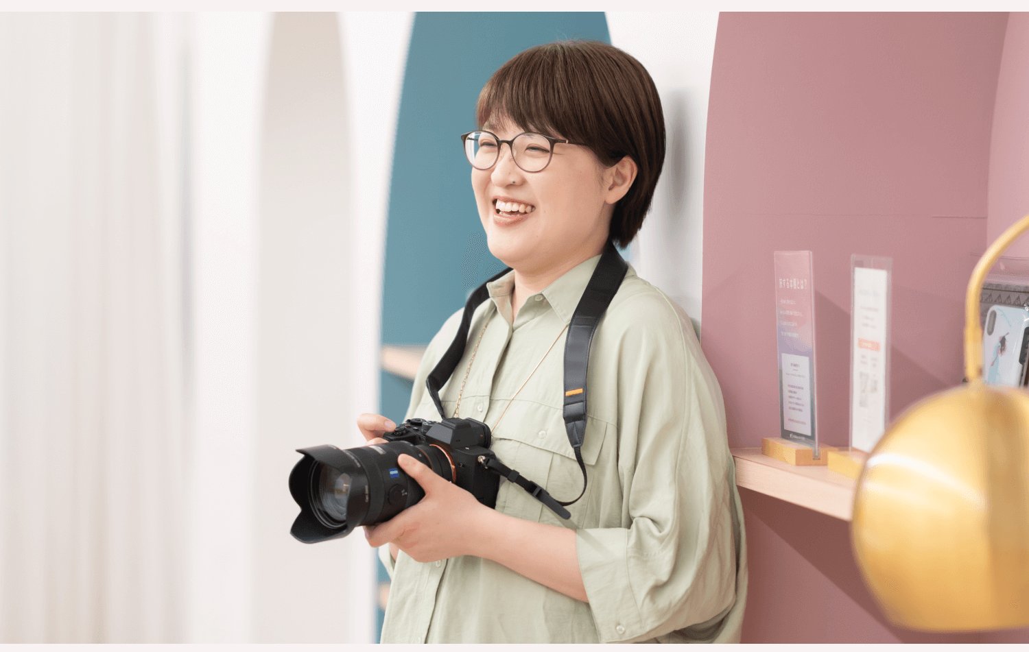 フォトスタジオの店内で笑顔でカメラを構えるnaokoさん