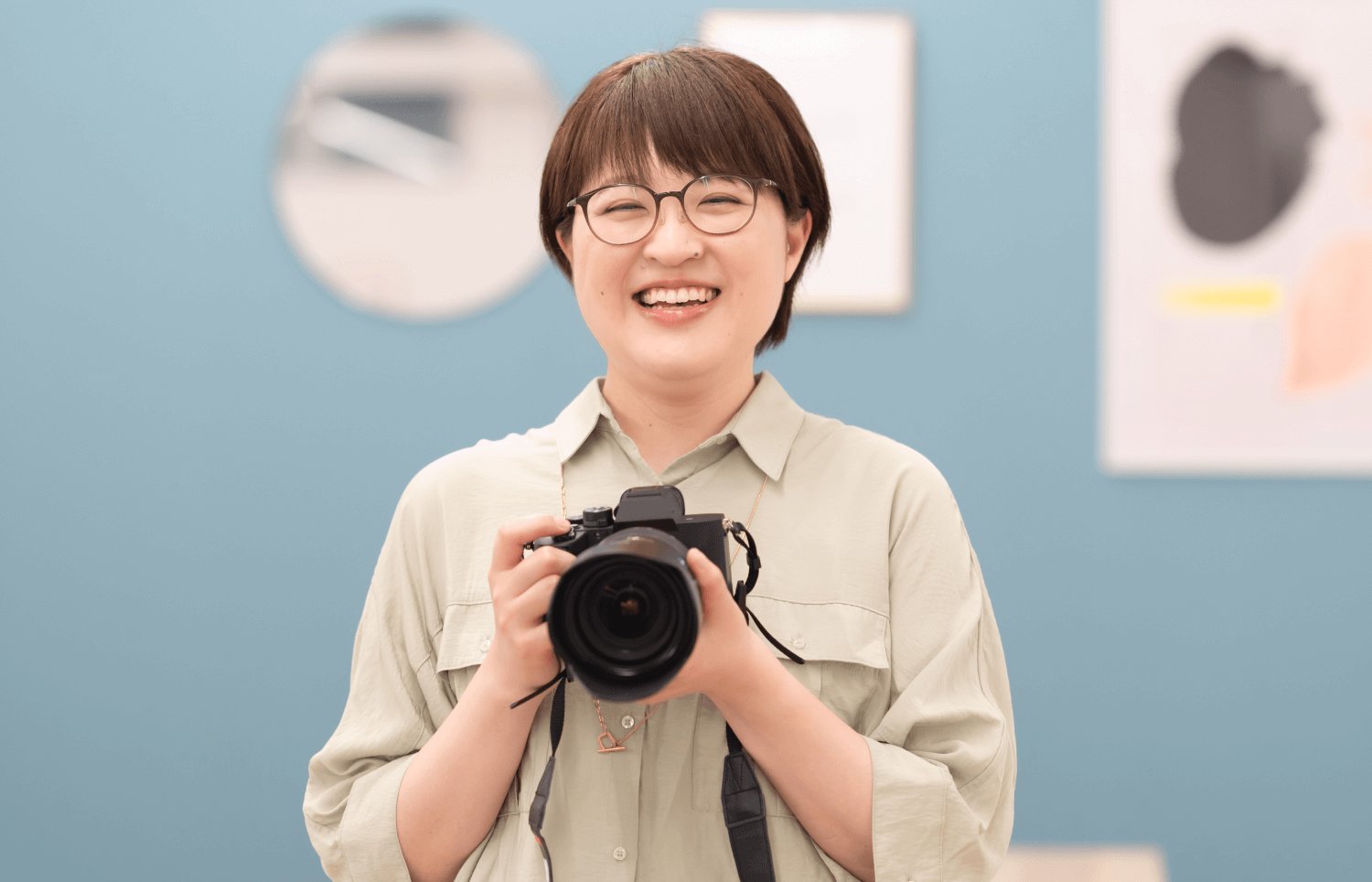 展示スペースでカメラを構えて笑顔のnaokoさん