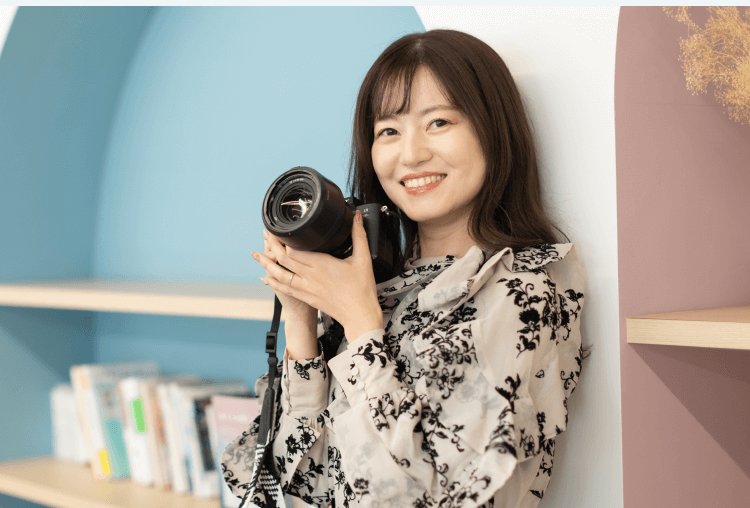 室内でカメラを構えるあきさんのポートレート