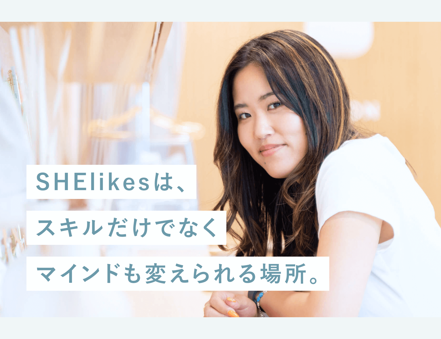 「SHElikesは、スキルだけでなくマインドも変えられる場所。」というteal文字のマーカー短冊が重なる、あみんこさんの写真