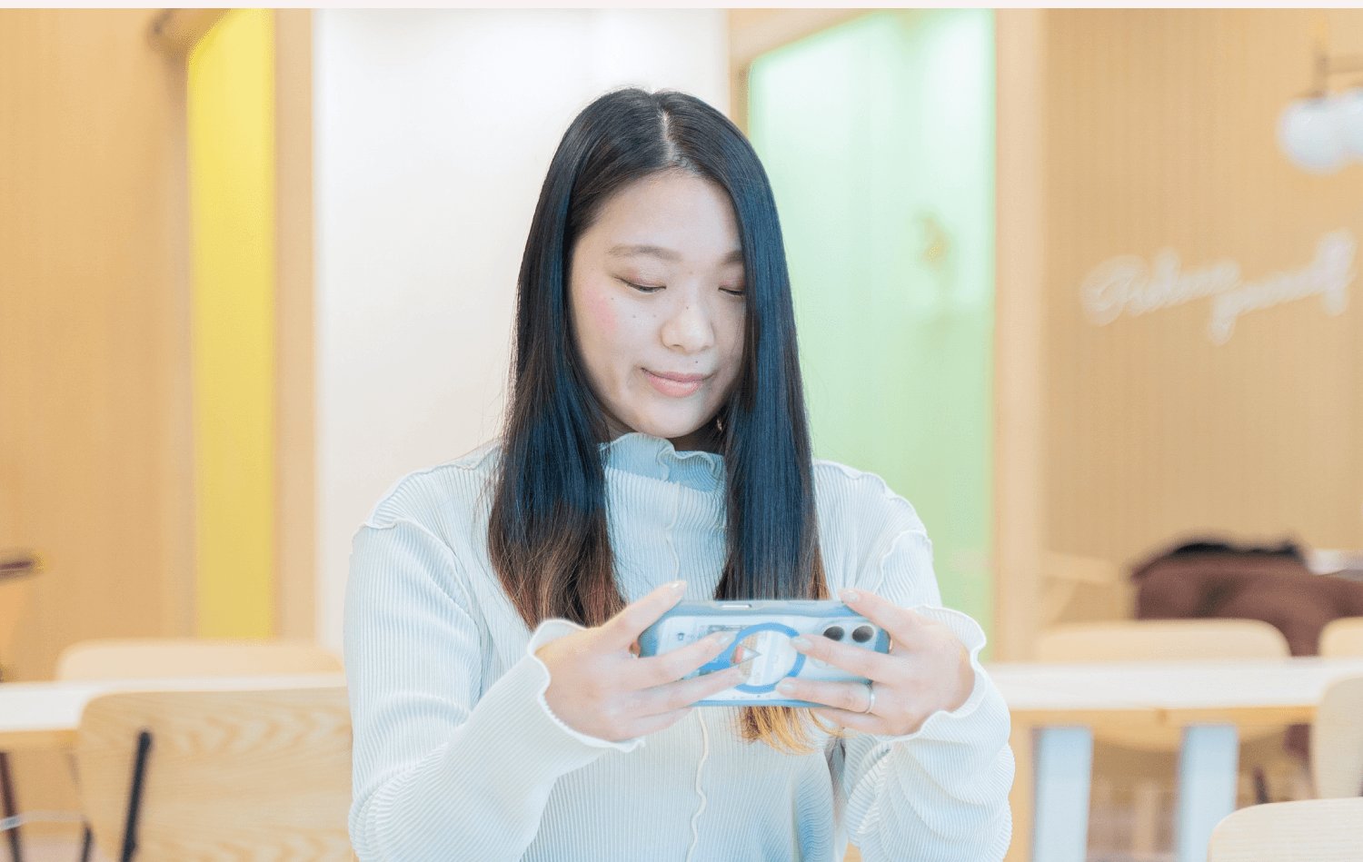 店内でスマートフォンを操作しながら微笑むかれんさんの写真