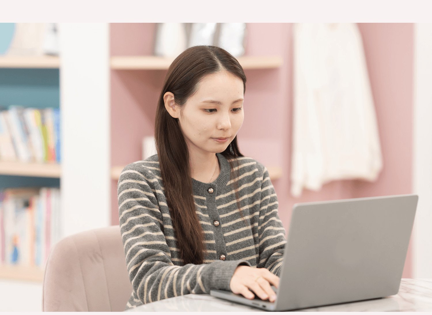 木目テーブルでノートPCを操作する莉央奈さん